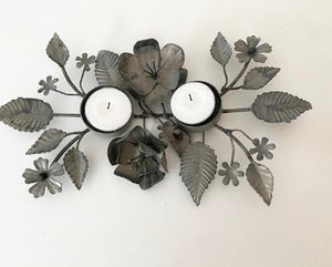 Antique zinc tealight holder with ornate leaves.